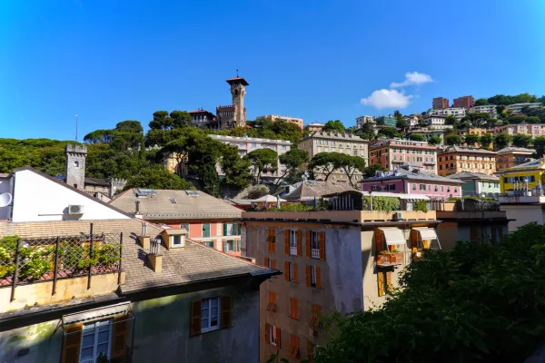 Façades colorées de Gênes, Italie, s'étendant sur un coteau ensoleillé sous un ciel bleu.