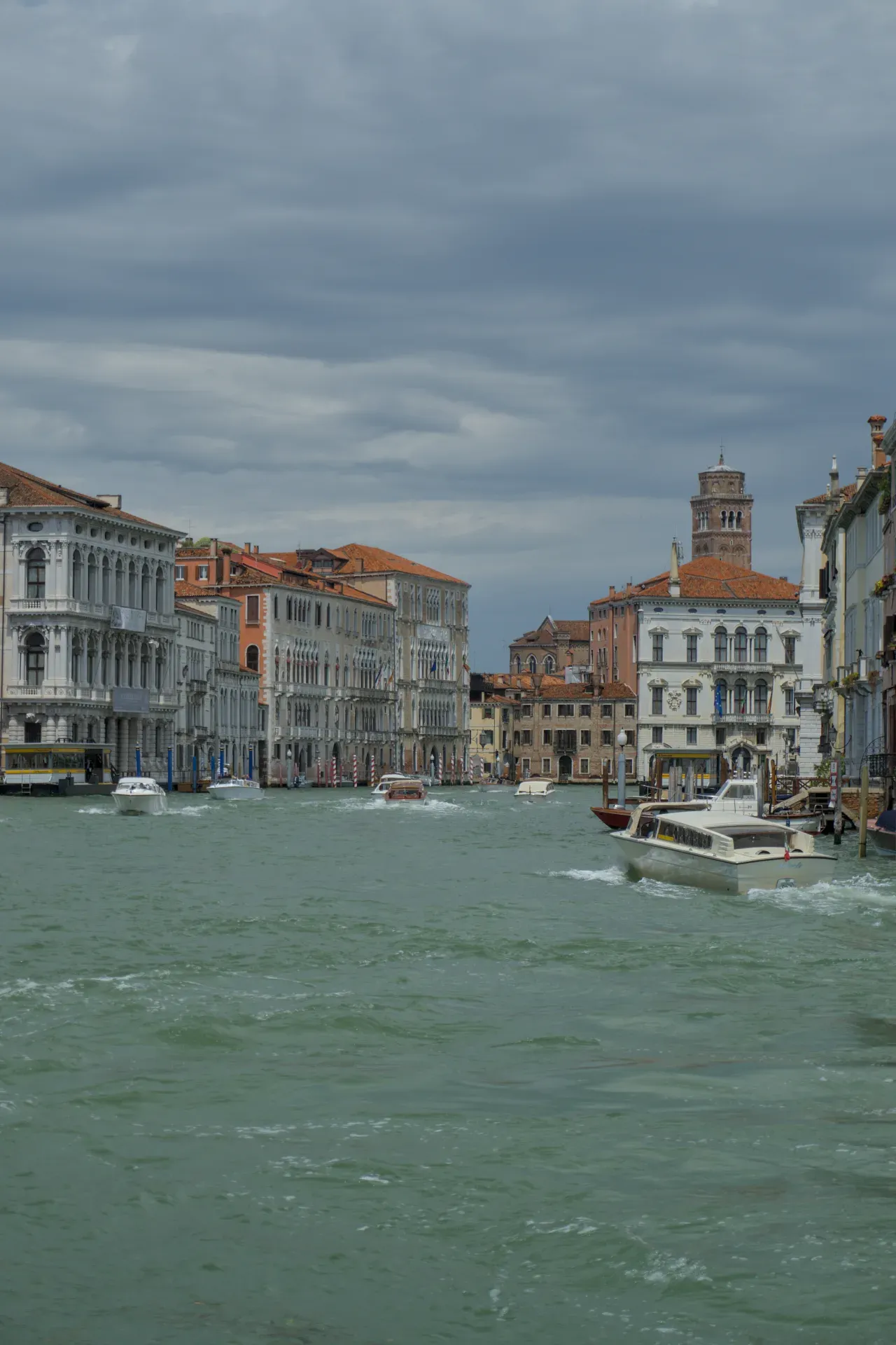 Grand Canal à Venise avec des bâtiments historiques et des bateaux sous un ciel dramatique.