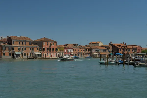 Vue du canal de Murano avec des maisons colorées et un bateau qui passe.