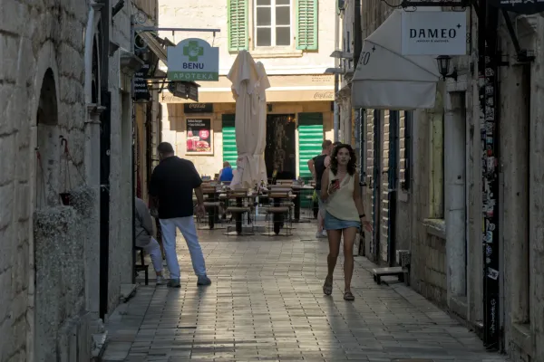 Una mujer pasea por una calle soleada del casco antiguo de Kotor, Montenegro.
