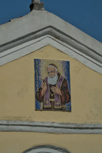 Detaljan mozaik bradatog sveca u ljubičastom ogrtaču na žutoj fasadi u Herceg Novom, Crna Gora.