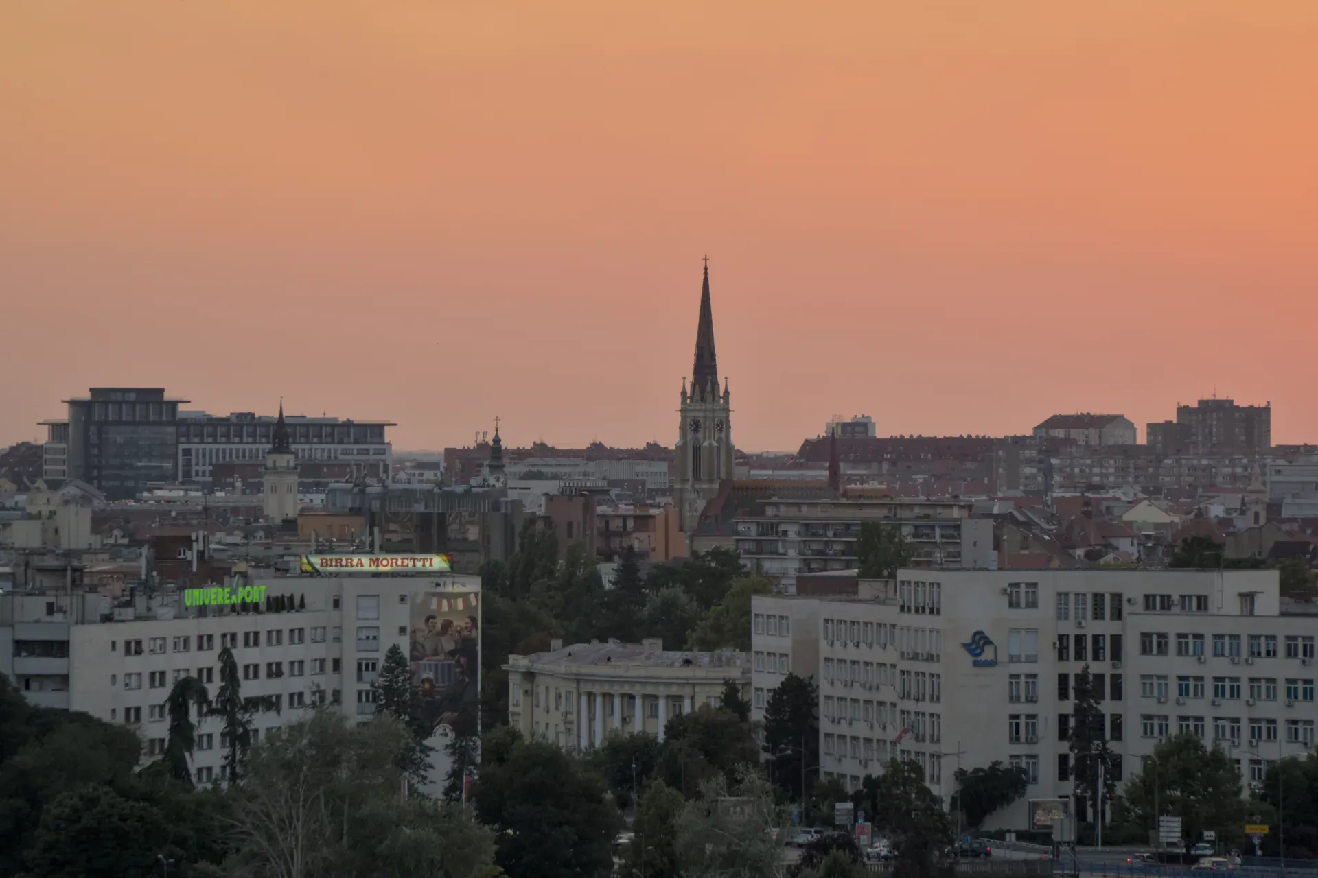 Panorama di Novi Sad al tramonto, vista dalla Fortezza di Petrovaradin, con campanili e paesaggio urbano.