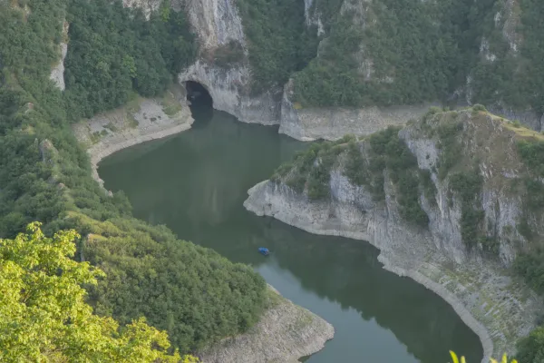 Die Uvac-Schlucht in Serbien zeigt gewundene Flussbiegungen und die Uschak-Höhle mit einem kleinen blauen Boot im Wasser.