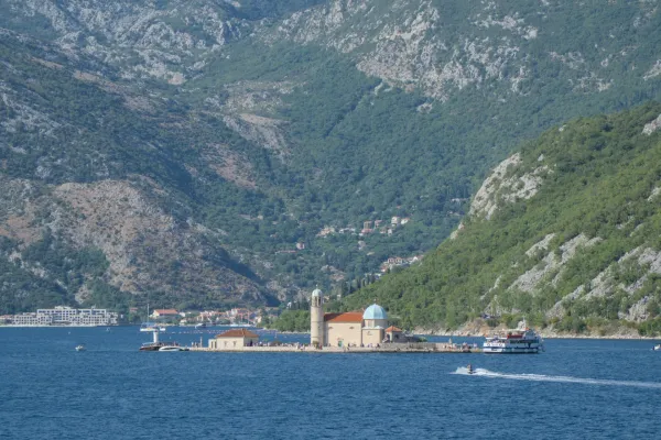View of the island Gospa od Škrpjela in Kotor, Montenegro, against a backdrop of mountains and sea.