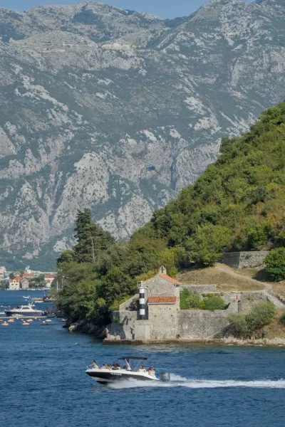 Lighthouse on the coast of the Bay of Kotor, Montenegro, with a boat on the water.