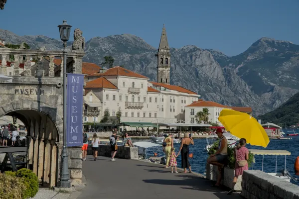 Šetalište Perasta sa istorijskim zgradama i planinama u pozadini.