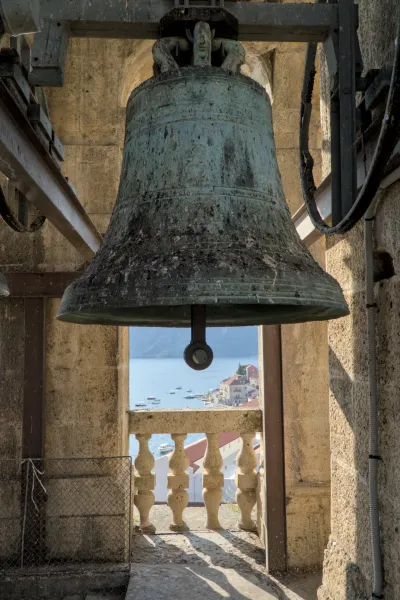 Une ancienne cloche dans une tour en pierre surplombant la ville côtière de Perast et la mer à Kotor.