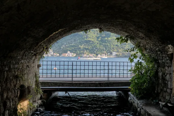 Sea view with a boat and architecture through a stone archway in Perast, Kotor.
