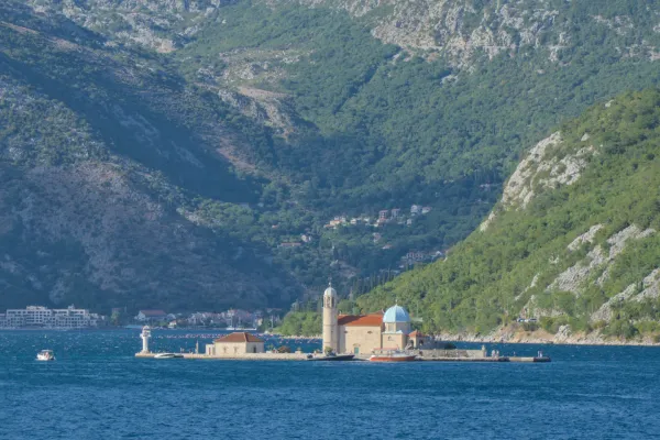 Island church Our Lady of the Rocks on the water, with green mountains in Kotor, Montenegro.