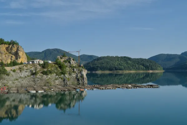 Jutarnja idila na Zaovinskom jezeru u Nacionalnom parku Tara, Srbija, sa mirnom vodom i pošumljenim brdima.