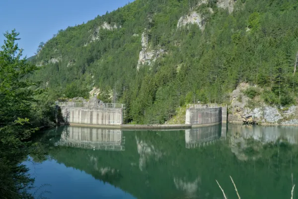 Der Spaiči-Damm in Zaovine, umgeben von grünen Bergen mit Spiegelungen im Wasser.