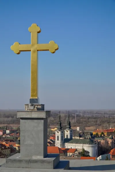 Istaknuti zlatni krst na pozadini jasnog plavog neba, sa panoramskim pogledom na Sremske Karlovce, Srbija.