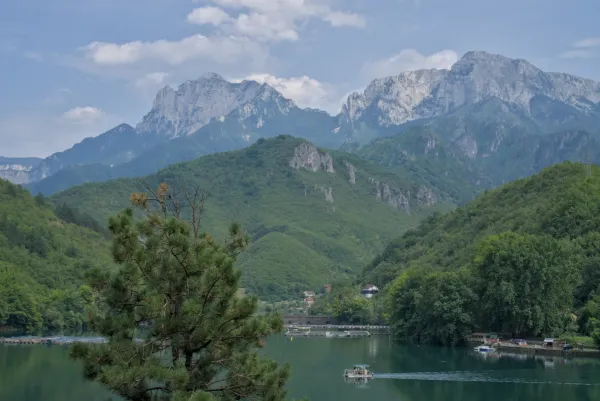 Čamac plovi prelepim jezerom sa zelenim planinama u pozadini, na putu za Mostar.