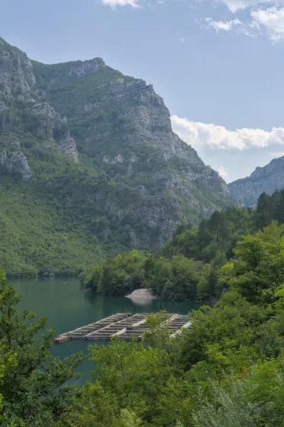 Lago con piscifactoría frente a majestuosas montañas, capturado en el camino de Sarajevo a Mostar.