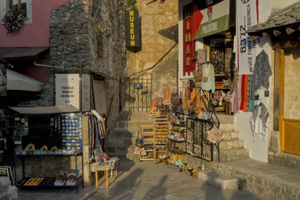 Rue atmosphérique de la vieille ville de Mostar à l'heure dorée, avec des boutiques d'artisans et des bâtiments en pierre.