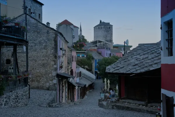 Une rue pavée dans la vieille ville de Mostar pendant l'heure avant l'aube, avec des bâtiments historiques dans un doux crépuscule.