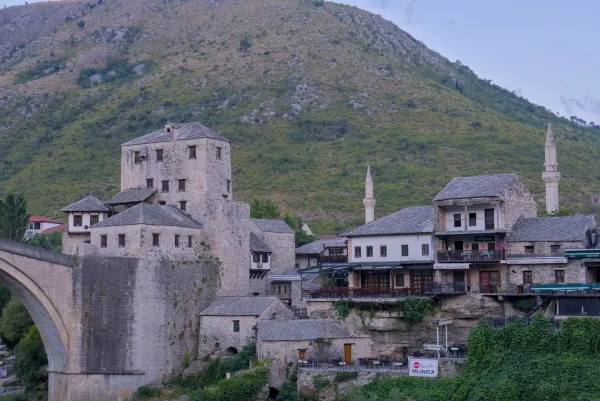 Tôt le matin dans la vieille ville de Mostar, montrant une architecture en pierre et des minarets sur une colline.