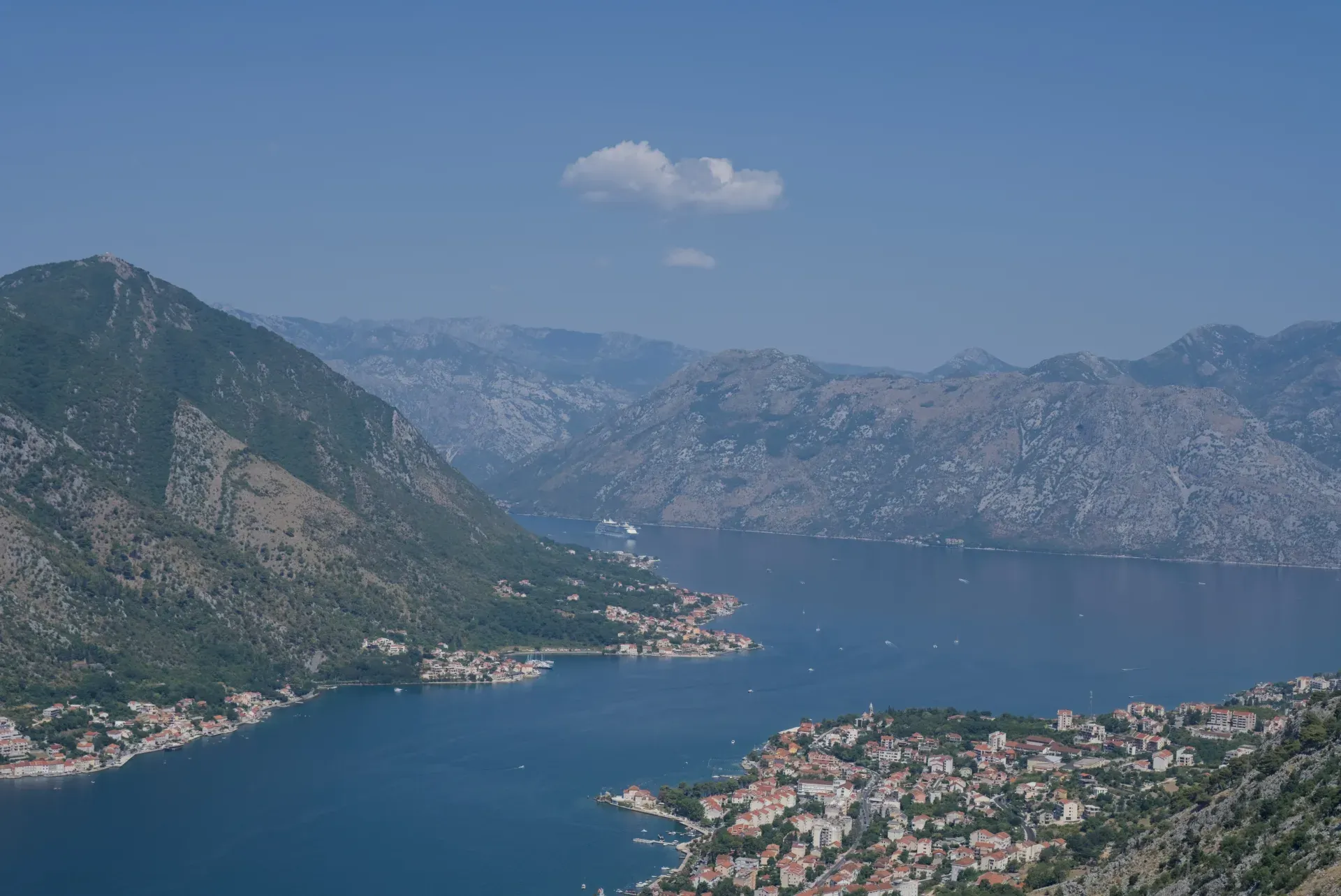 Pogled iz ptičje perspektive na kruzer koji ulazi u Boko-kotorski zaliv, sa pogledom na primorske gradove Dobrotu i Prčanj.