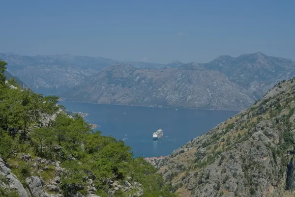 View of Kotor Bay in Montenegro from the mountain through rocks, with a cruise ship in the water.