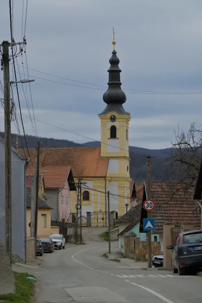 L'Église de la Transfiguration à Beočin, Serbie, avec son clocher jaune et blanc distinctif, sous un ciel couvert.
