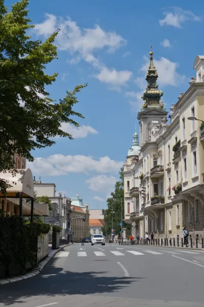 Belgrade street with Baroque architecture and an Orthodox cathedral under a clear sky.