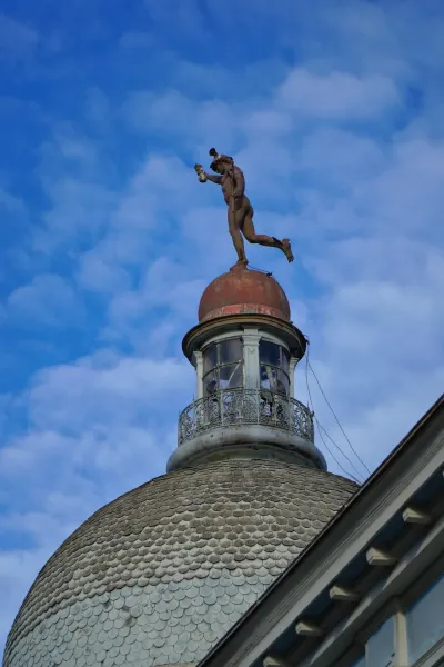 Statue of Mercury, god of commerce, atop the dome of the National Bank of Serbia in Novi Sad against a blue sky.