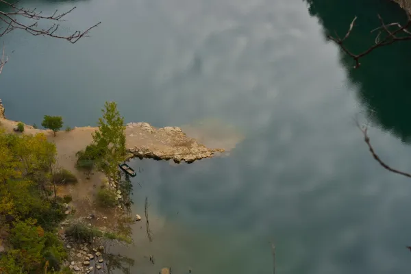 Boot am Ufer des Ledinačko-Sees, der den bewölkten Morgenhimmel widerspiegelt.