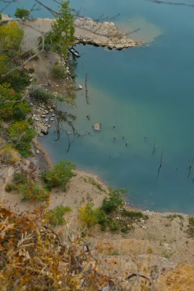 Ein Boot ist am Ufer des Ledinačko-Sees mit klarem Wasser angedockt, aus der Höhe aufgenommen.