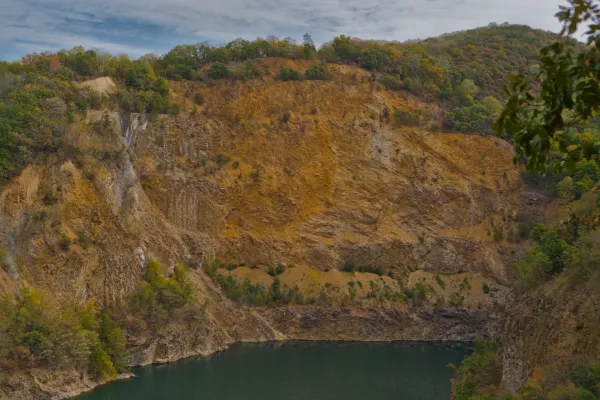 Steep cliffs and quarry around Ledinačko Lake, Serbia, with ochre tones and green vegetation.