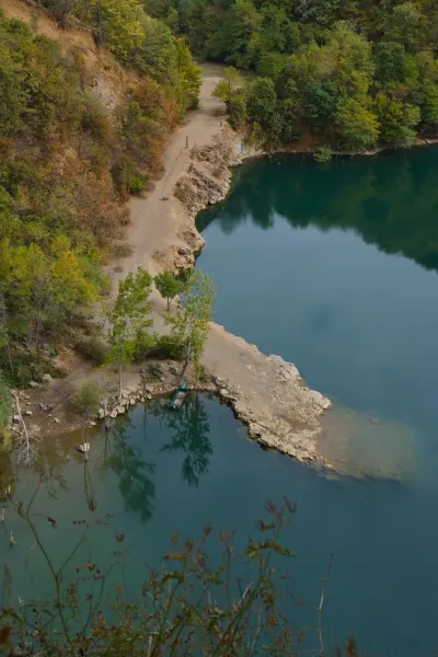 A boat moored on the shore of Ledinačko Lake in Serbia, surrounded by greenery and rocks.