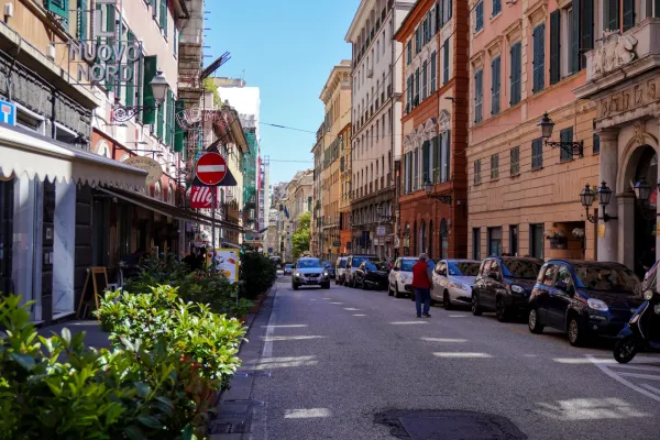 Ulica Via Balbi u Đenovi, Italija, sa istorijskim zgradama, parkiranim automobilima i hotelskim oznakama.