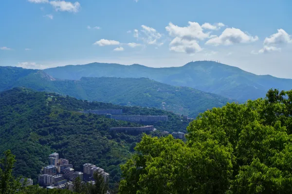 Pogled na zelene bregove u blizini Đenove, Italija, sa selom i modernim betonskim vijaduktom.