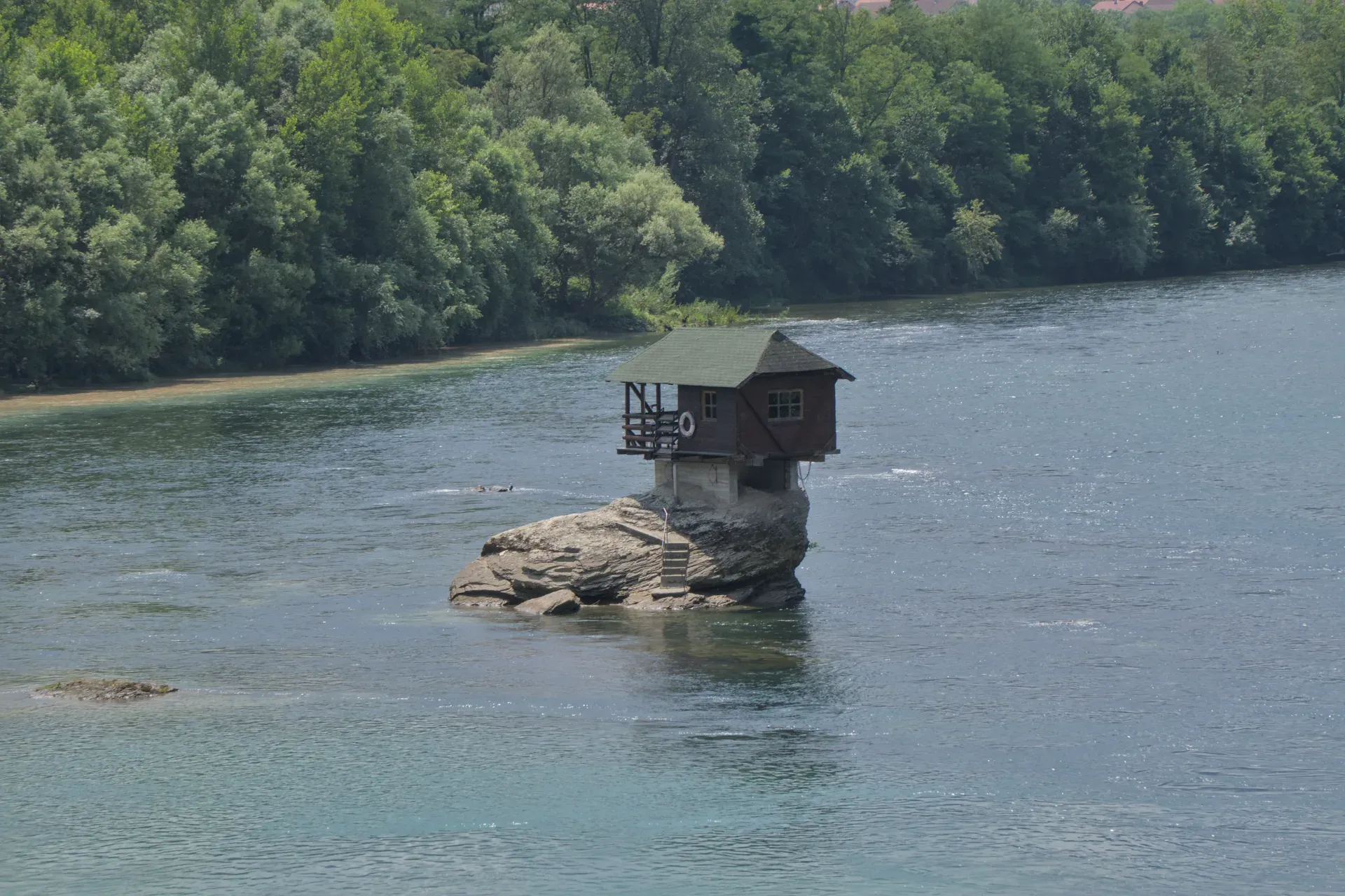 Das Haus an der Drina, ein kleines Holzhaus, das auf einem Felsen im Fluss Drina steht, mit Bäumen im Hintergrund im Nationalpark Tara, Serbien.
