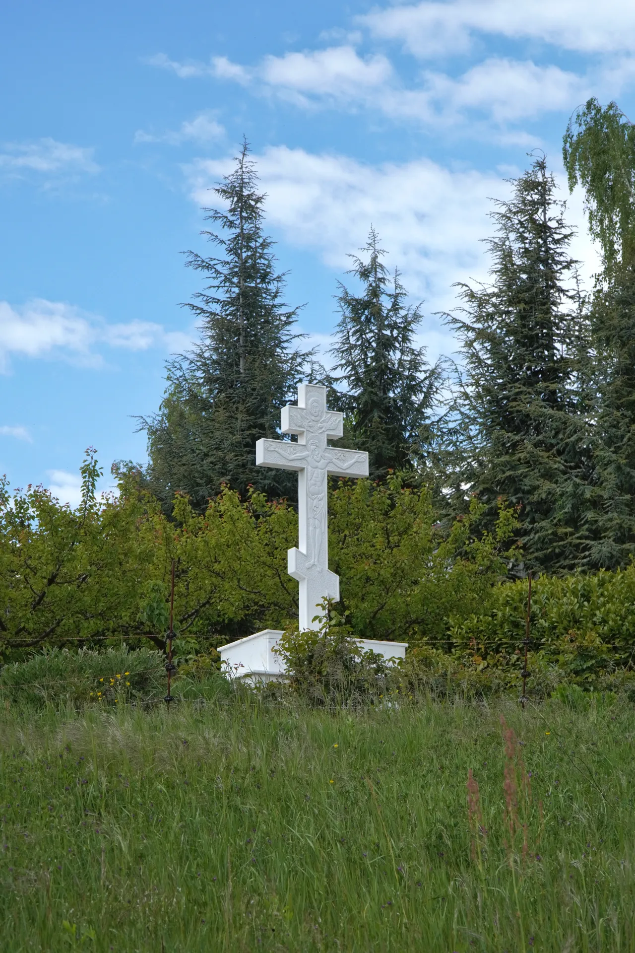 A white Orthodox cross is visible on a hillside with trees and grass, located on Fruška Gora, near Stari Hopovo, Novi Sad, Serbia.