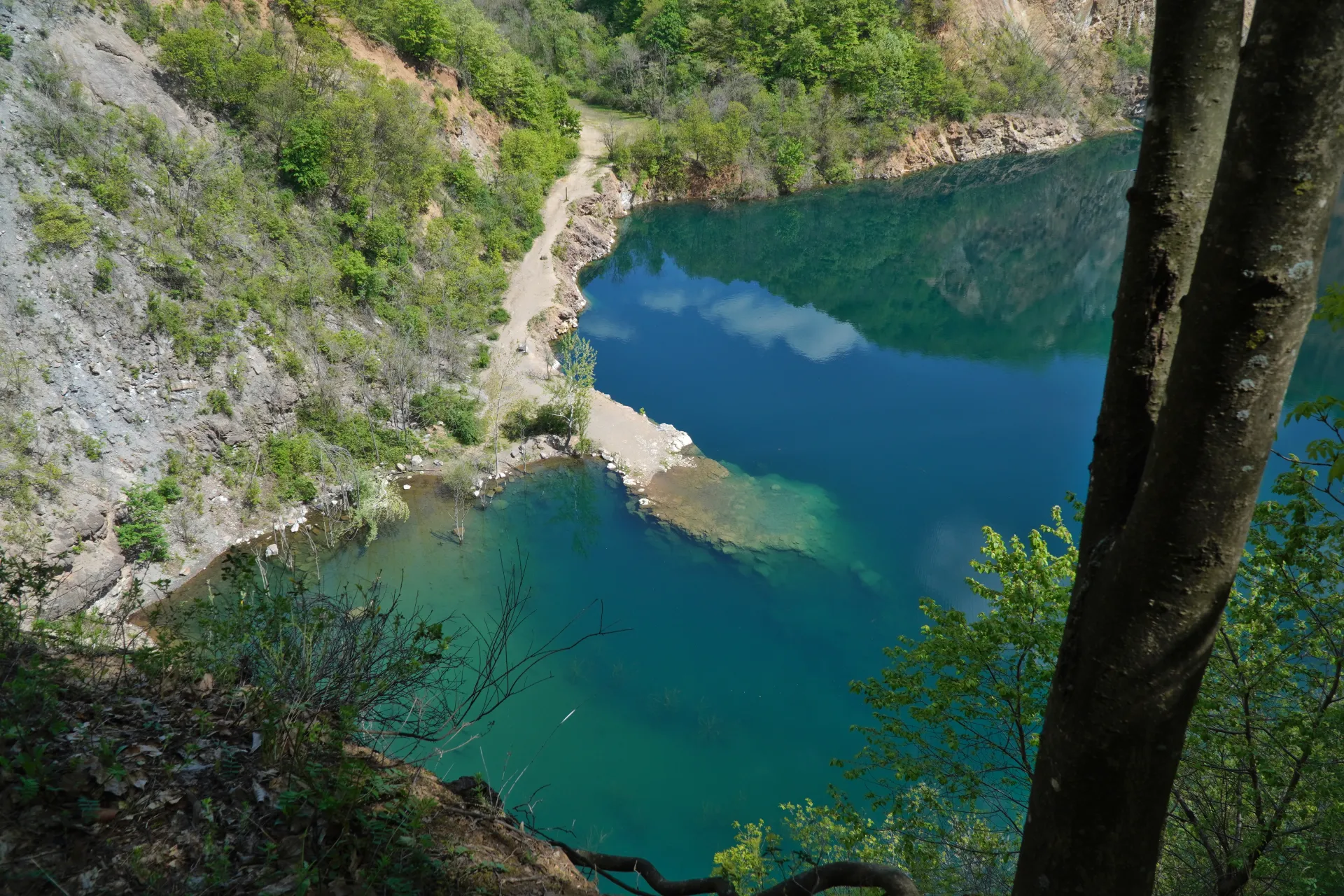 Scenic view of Ledićko Lake in Novi Sad, Serbia, with its clear blue-green water, rocky shores, and surrounding trees.