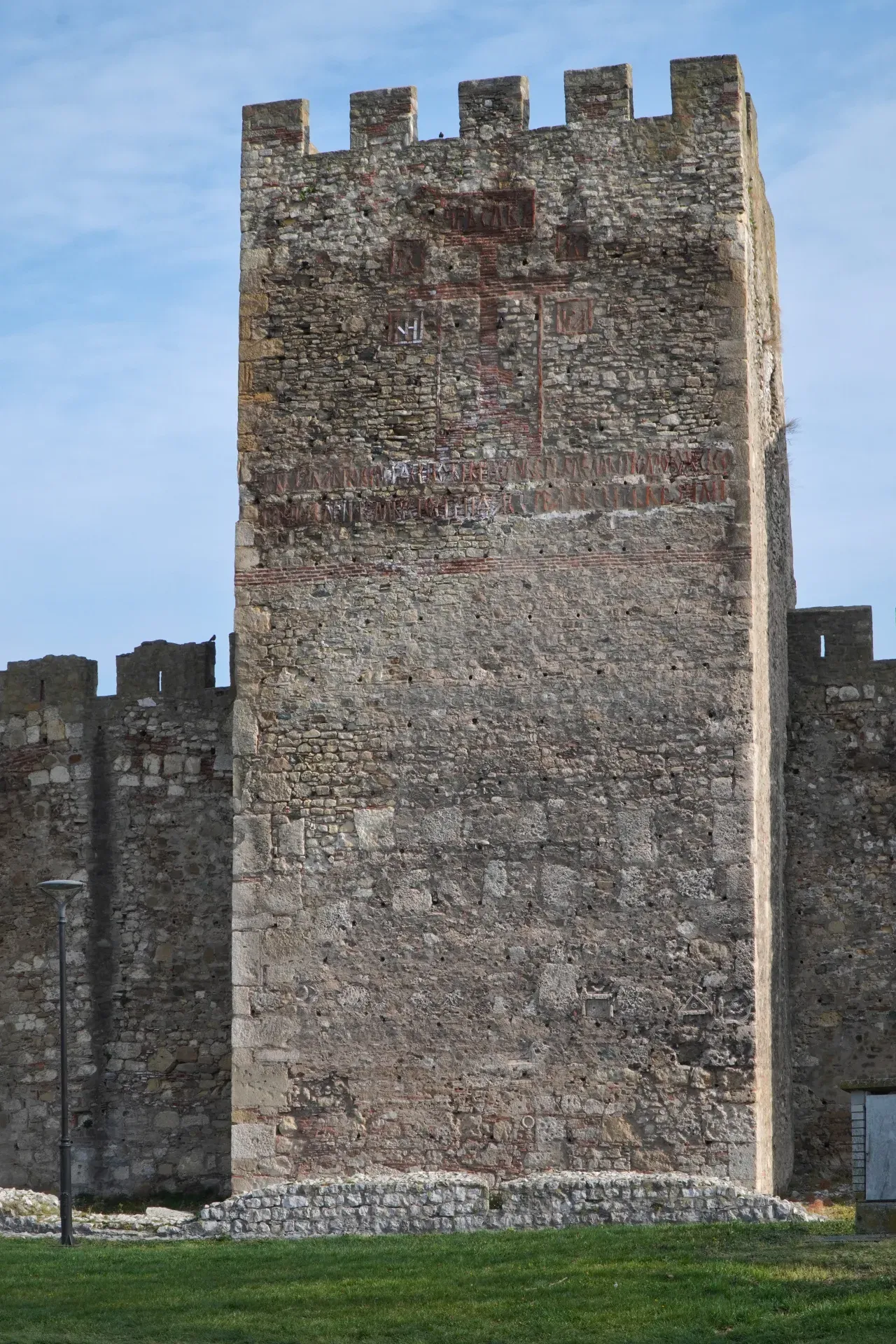 A massive stone tower with battlements of the Smederevo Fortress, Serbia, under a blue sky.