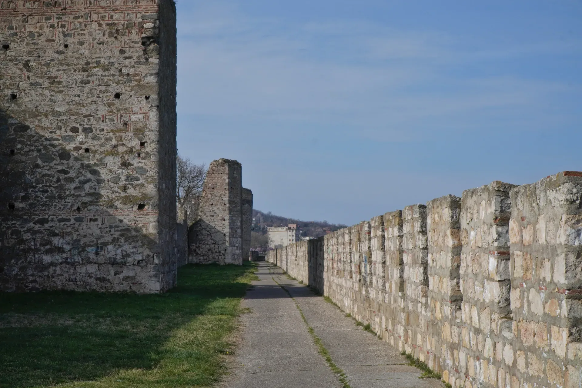 A path winds through the fortress walls of Smederevo, Serbia, with stone towers and a city in the background.