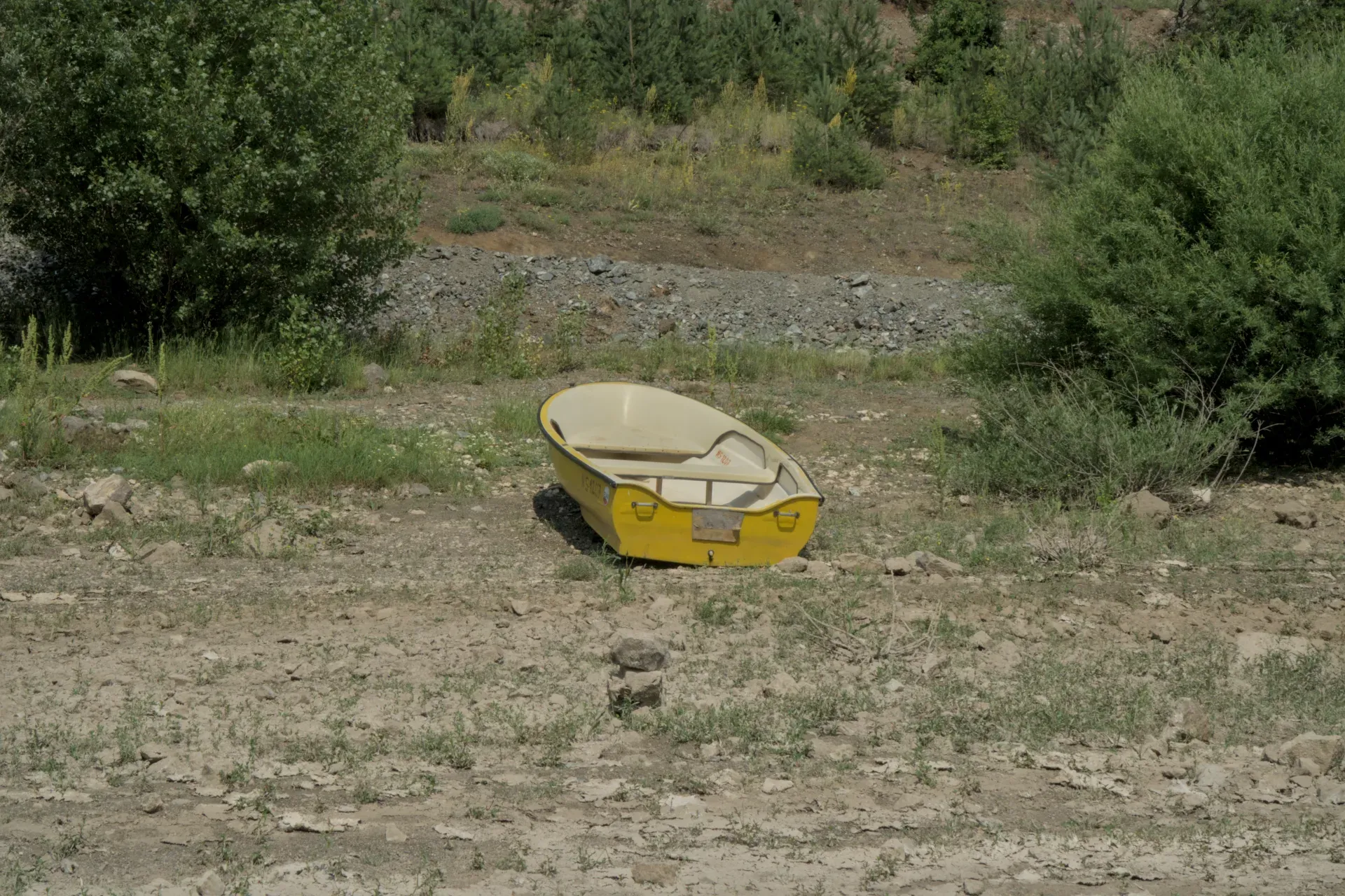 A yellow boat lies on the rocky shore of Lake Zaovine, surrounded by green vegetation, in Tara National Park, Serbia.