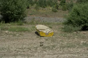 Un barco amarillo descansa en la orilla rocosa del lago Zaovine, rodeado de vegetación verde, en el Parque Nacional de Tara, Serbia.
