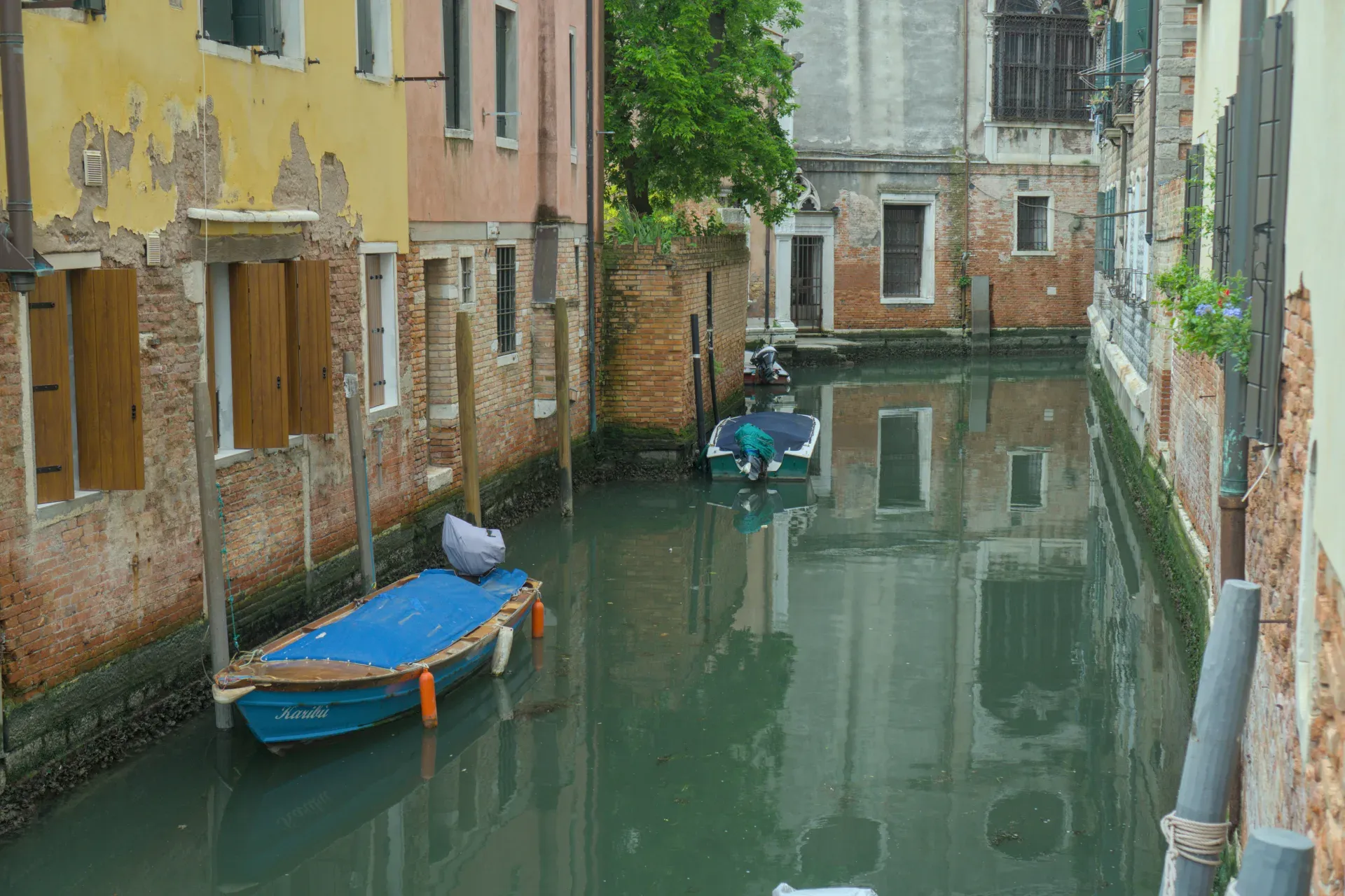 A picturesque canal in Venice, with traditional boats and historic buildings reflected in the water.