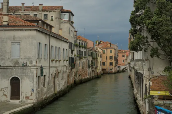 Ein enger Kanal in Venedig mit historischen Gebäuden und einem dramatischen, wolkenverhangenen Himmel.