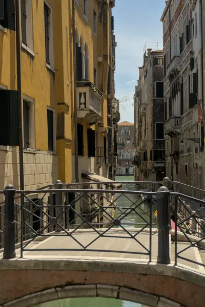Venecijanski kanal sa lučnim mostom, okružen starim, šarenim zgradama i jasnim nebom.