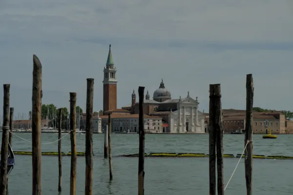 Crkva San Giorgio Maggiore u Veneciji, Italija, sa svojim karakterističnim tornjem, vidjena preko vode sa drvenih stubova u prvom planu.