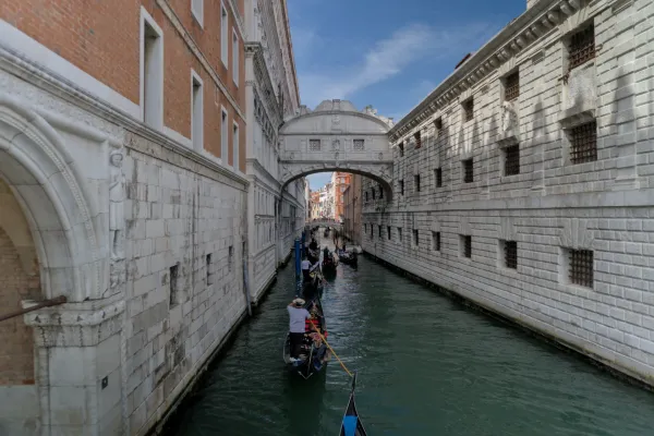 Gondeln fahren durch einen Kanal in Venedig, Italien, unter einer historischen Brücke hindurch.