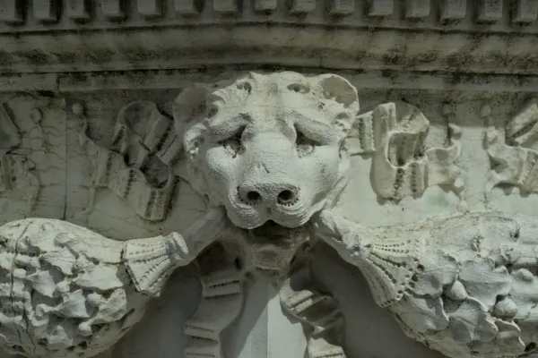 Altes Steinrelief eines Löwenkopfes mit seinen Pranken an einem Brunnen in Venedig.