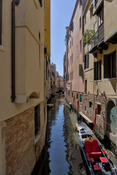 Ein venezianischer Kanal mit einer Gondel, umgeben von historischen Gebäuden, im Hochformat.