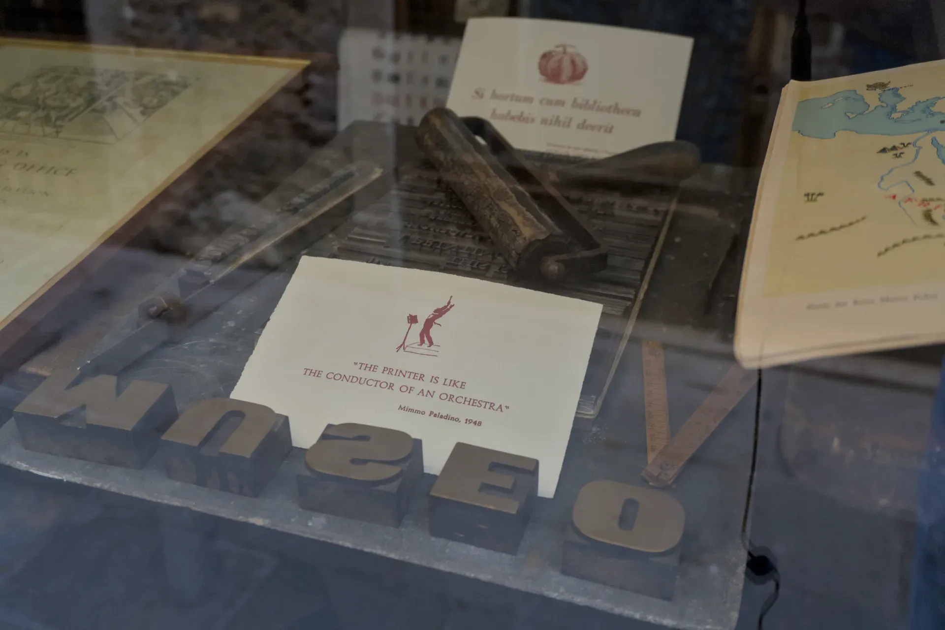 Antique printing press artifacts in Venice, including lead letters and a printing tool, displayed behind glass.
