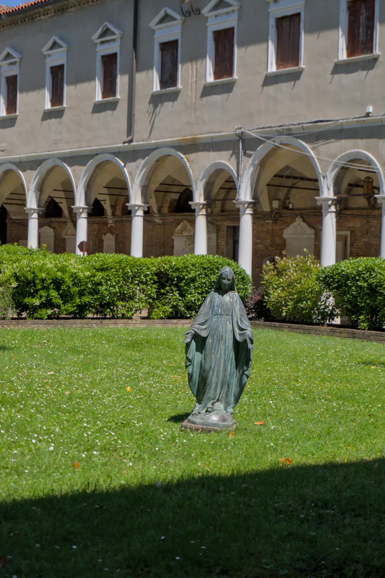 Bronze statue of the Madonna in the courtyard of San Michele Cemetery in Venice.