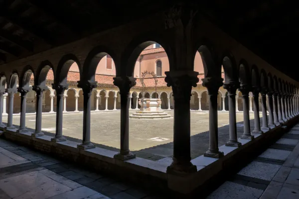 Architektonischer Innenhof auf dem Friedhof San Michele in Venedig mit Bögen, Säulen und einem Brunnen.