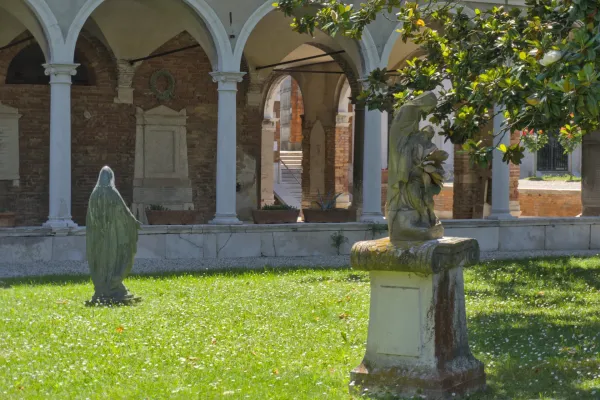 Groblje San Michele Venecija sa skulpturama i arkadama na suncu.